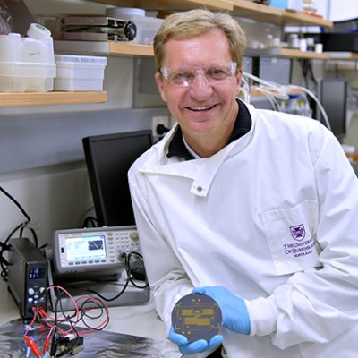 A scientist wearing a lab coat and holding a piece of equipment